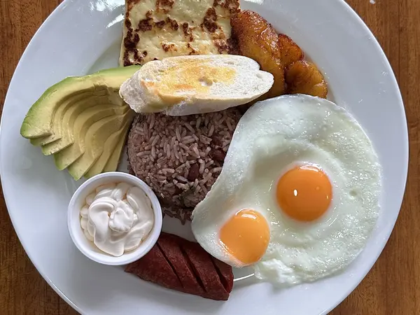 Desayuno típico con gallo pinto, dos huevos fritos, queso frito, plátano maduro, aguacate, natilla y salchichón (Al Punto)