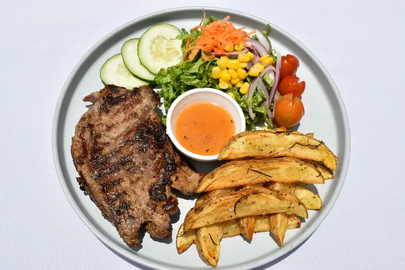 Churrasco a la parrilla con papas gajo, ensalada y aderezo