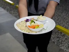 Pescado en salsa blanca con vegetales, servido por el personal del restaurante